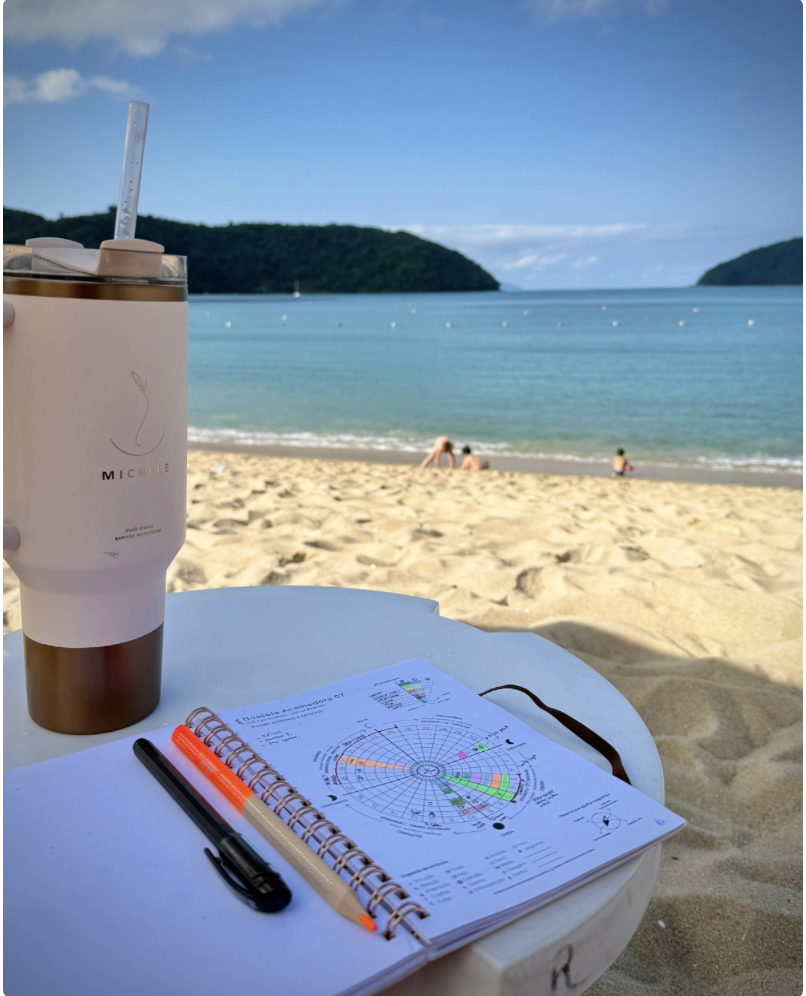 Praia,crianças brincando na areia e uma mesa com um caderno  de anotações.